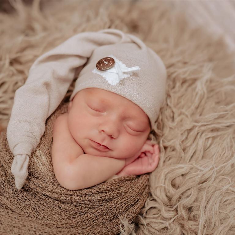 Neugeborenenfotos im Studio können auch ganz entspannt sein: süß träumend, wohlig eingepackt auf dem Fell